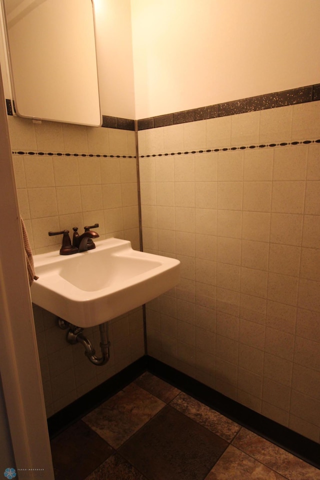 bathroom featuring tile walls, a sink, and a wainscoted wall