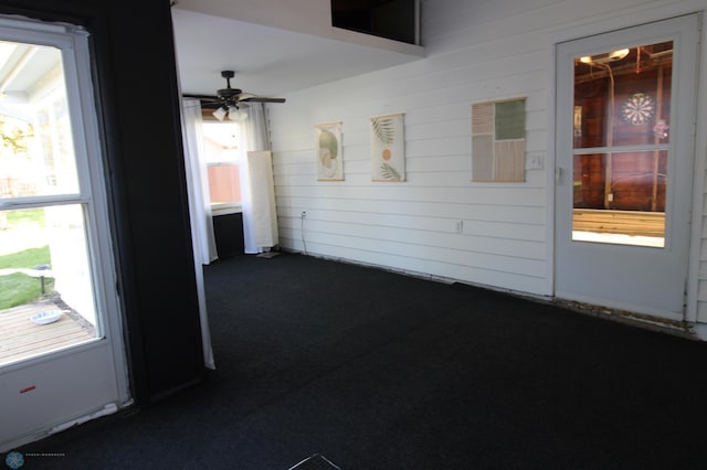 hallway featuring dark carpet and wood walls