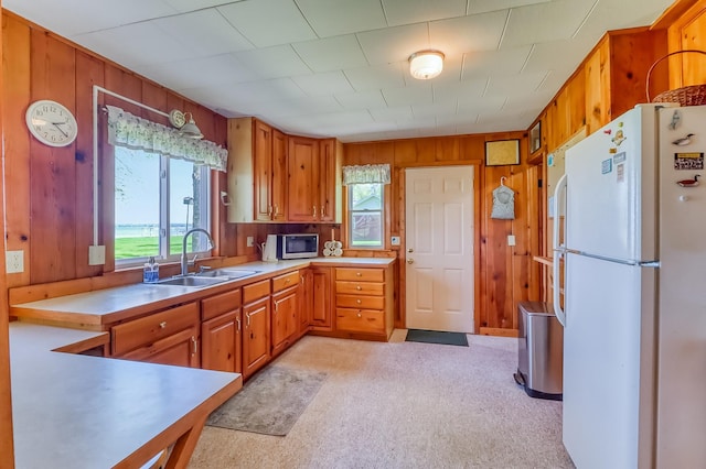 23620 Melissa Dr, Lake View Twp, MN 56501 - kitchen featuring freestanding refrigerator, a sink, stainless steel microwave, wooden walls, and brown cabinetry