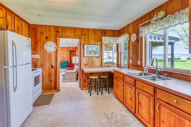 23620 Melissa Dr, Lake View Twp, MN 56501 - kitchen with white appliances, a sink, brown cabinets, wooden walls, and light countertops