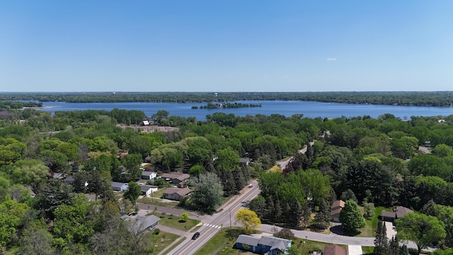 drone / aerial view of a nearby body of water and a heavily wooded area