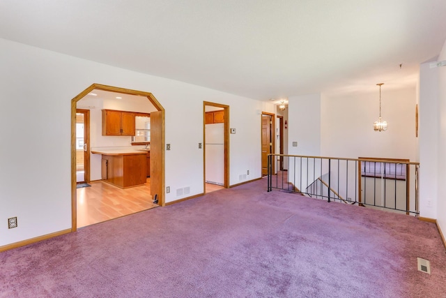 5391 Cottage Ave, White Bear Twp, MN 55110 - spare room with light colored carpet, arched walkways, and a chandelier
