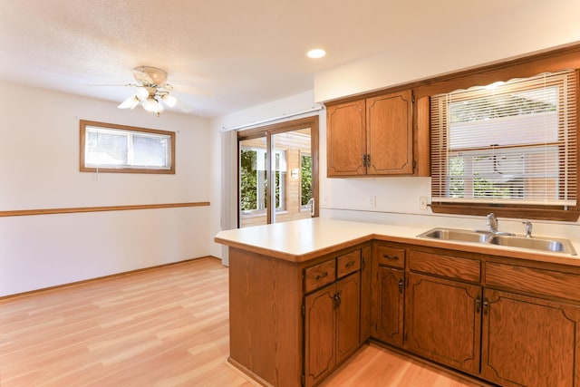 5391 Cottage Ave, White Bear Twp, MN 55110 - kitchen featuring a peninsula, brown cabinetry, light countertops, light wood-style flooring, and ceiling fan