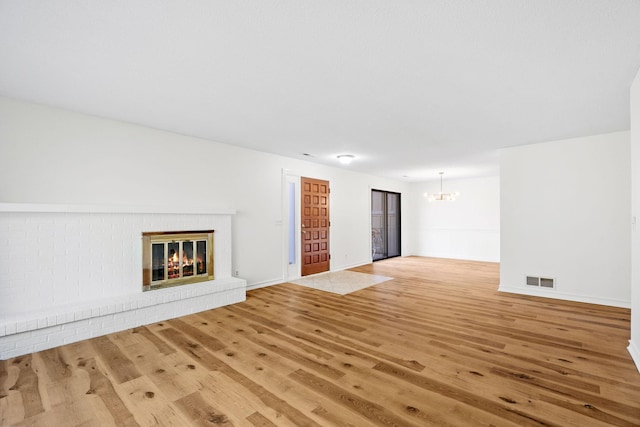 9018 Neill Lake Rd, Eden Prairie, MN 55347 - unfurnished living room with a chandelier, light wood-type flooring, a brick fireplace, and baseboards