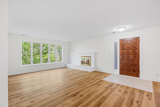 9018 Neill Lake Rd, Eden Prairie, MN 55347 - unfurnished living room featuring light wood-style flooring, a glass covered fireplace, and baseboards