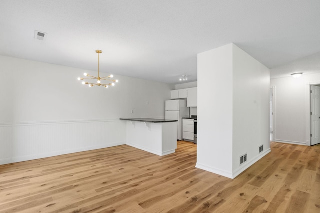 9018 Neill Lake Rd, Eden Prairie, MN 55347 - unfurnished living room featuring light wood-type flooring, a chandelier, a wainscoted wall, and baseboards