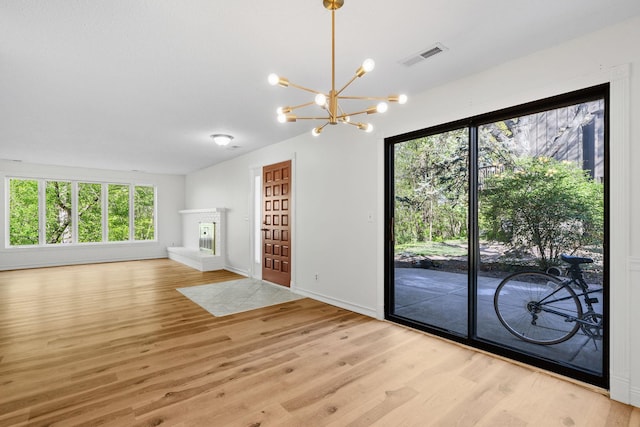 9018 Neill Lake Rd, Eden Prairie, MN 55347 - unfurnished living room with light wood finished floors, a chandelier, healthy amount of natural light, and baseboards