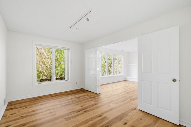 9018 Neill Lake Rd, Eden Prairie, MN 55347 - empty room featuring rail lighting, plenty of natural light, and light wood-type flooring