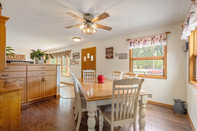 dining space featuring dark wood-type flooring, ceiling fan, baseboards, and a textured ceiling