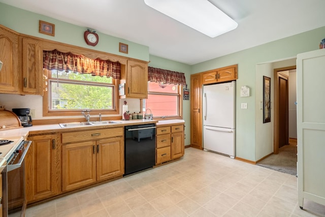 kitchen featuring freestanding refrigerator, a sink, dishwasher, and light countertops