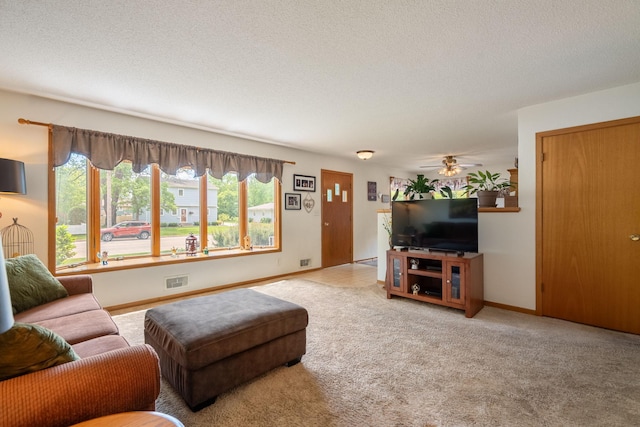 living room with carpet floors, baseboards, ceiling fan, and a textured ceiling
