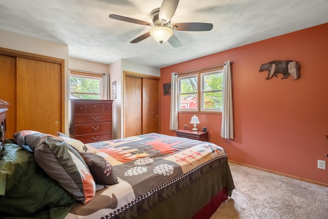 bedroom with two closets, carpet flooring, multiple windows, and baseboards