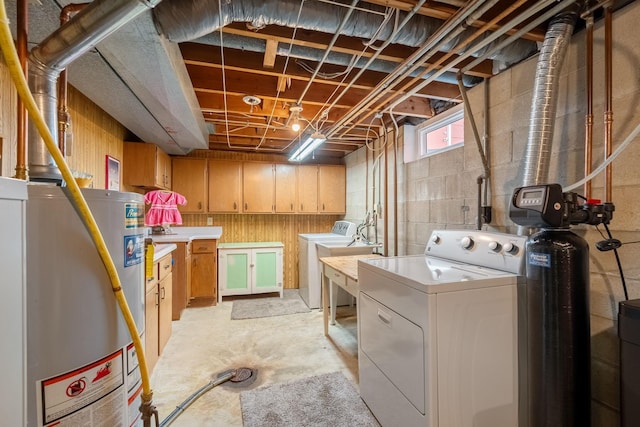 laundry area featuring water heater, washer and clothes dryer, and concrete block wall