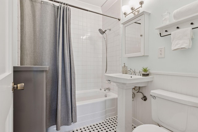 bathroom featuring toilet, wainscoting, and shower / bath combo
