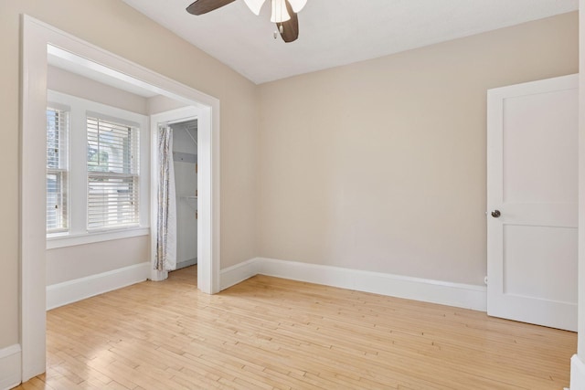 spare room with a ceiling fan, light wood-style flooring, and baseboards