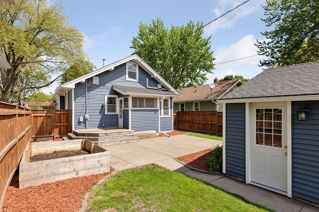 rear view of property with a garden, a fenced backyard, a patio, a shingled roof, and an outdoor structure