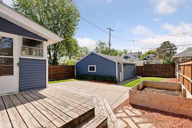 wooden terrace with a vegetable garden, a fenced backyard, and an outbuilding