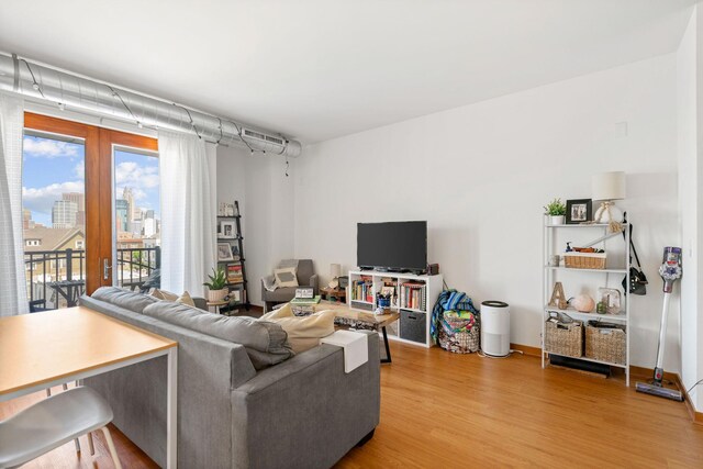 living area featuring light wood-type flooring, baseboards, and a view of city