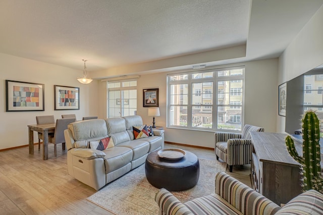 living room with light wood-type flooring, baseboards, and a textured ceiling