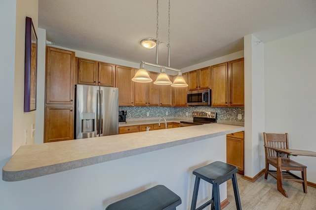 kitchen featuring stainless steel appliances, brown cabinetry, decorative backsplash, light countertops, and light wood-style flooring