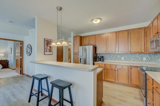 kitchen with stainless steel appliances, a kitchen breakfast bar, light wood-type flooring, and light countertops