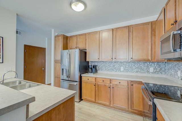 kitchen featuring stainless steel appliances, a sink, backsplash, and light countertops