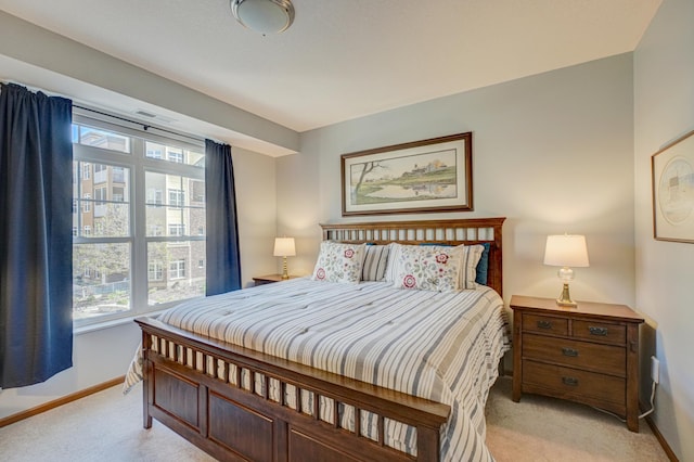 bedroom featuring light colored carpet, baseboards, and multiple windows
