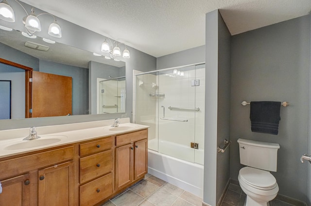 bathroom with tile patterned flooring, toilet, double vanity, a textured ceiling, and baseboards