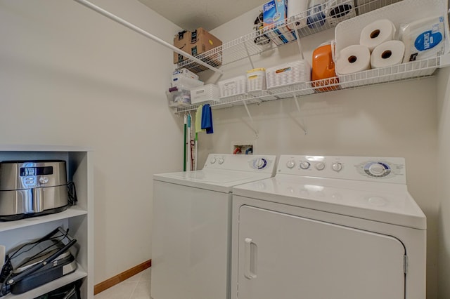 clothes washing area with separate washer and dryer, light tile patterned floors, and baseboards