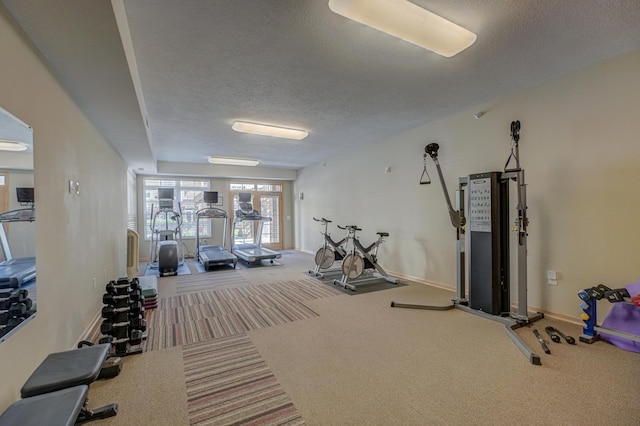 workout area with carpet flooring, a textured ceiling, and baseboards
