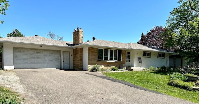 ranch-style home featuring a garage, a chimney, driveway, a front lawn, and stone siding