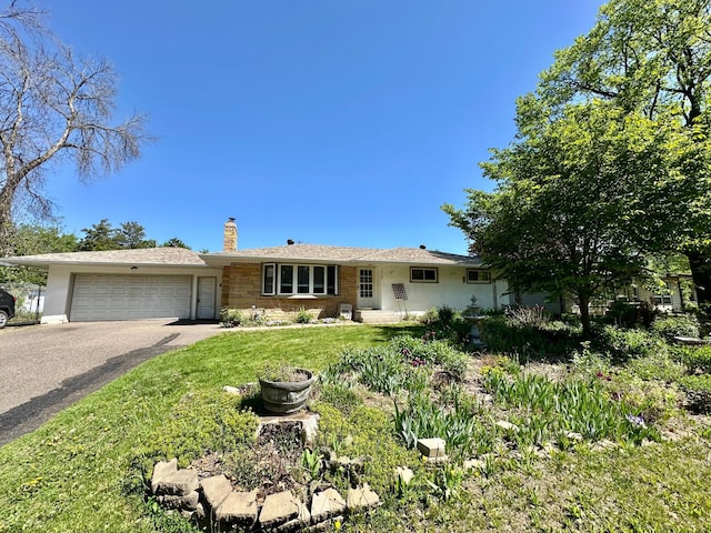 ranch-style home with a chimney, an attached garage, asphalt driveway, and a front yard
