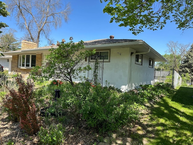 view of side of home featuring a chimney and stucco siding