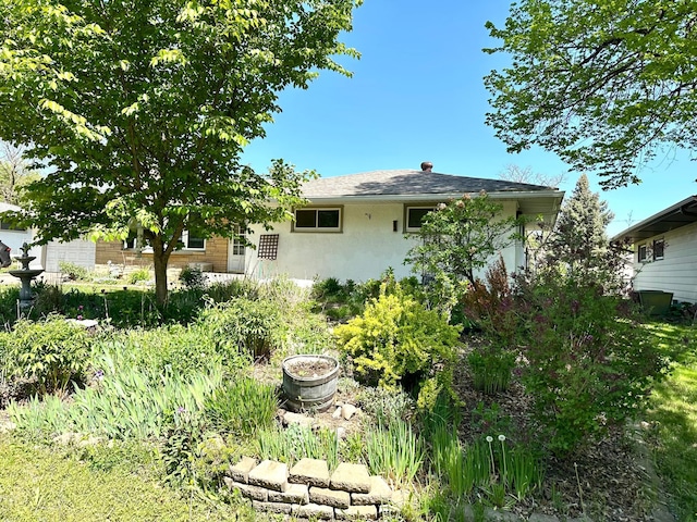 rear view of property with stucco siding and roof with shingles