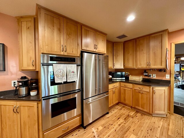 kitchen featuring stainless steel appliances, light wood-style flooring, dark countertops, and recessed lighting