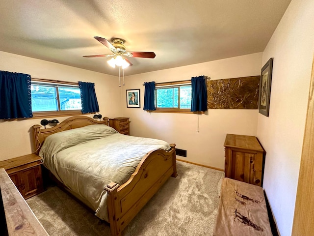 carpeted bedroom with multiple windows, a ceiling fan, and baseboards