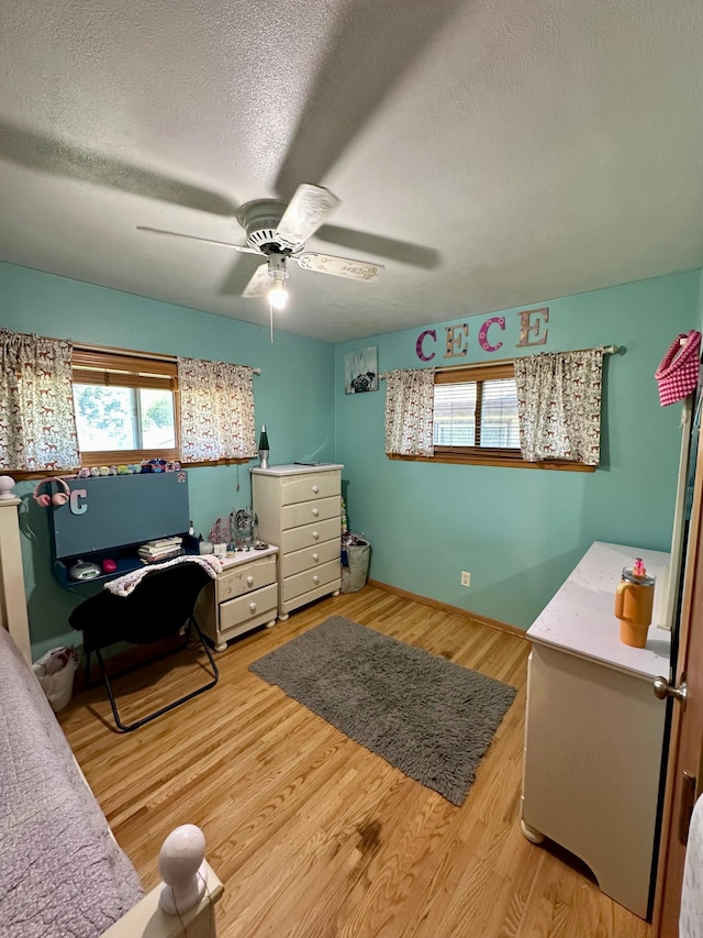 bedroom featuring a textured ceiling, light wood-style floors, ceiling fan, and an office area