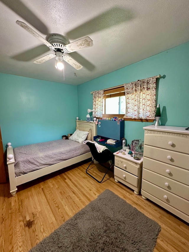 bedroom featuring wood finished floors, a ceiling fan, and a textured ceiling