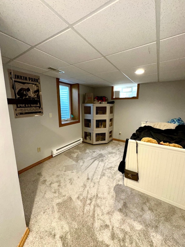 carpeted bedroom with baseboard heating, a paneled ceiling, and baseboards