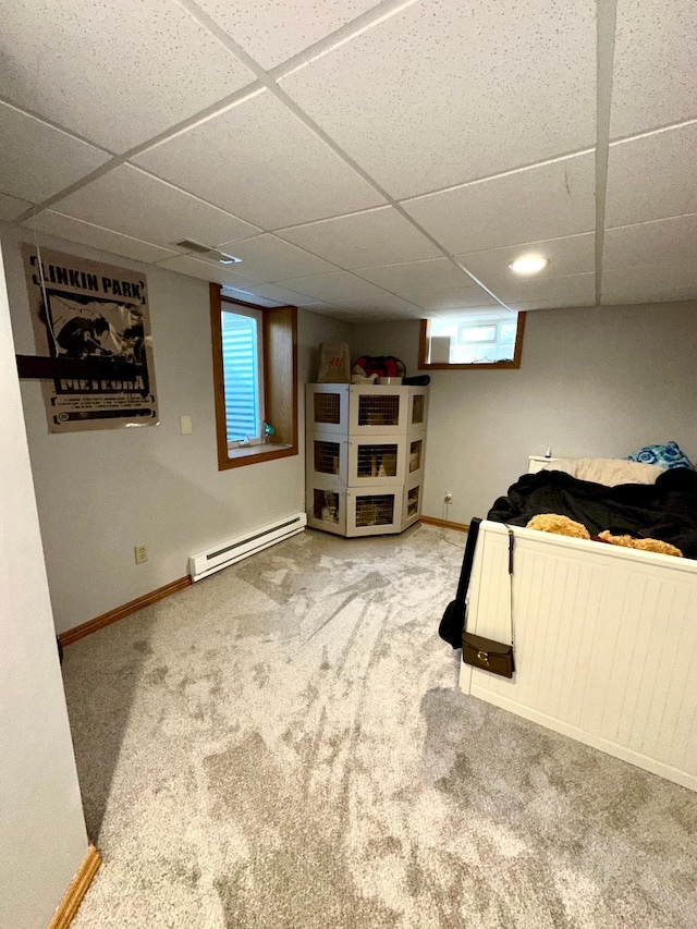 bedroom featuring baseboard heating, a drop ceiling, carpet flooring, and baseboards