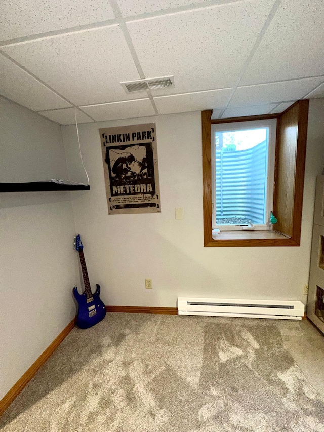 basement with a paneled ceiling, a baseboard heating unit, carpet, and baseboards