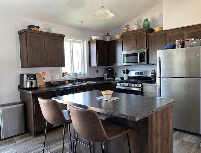 kitchen with stainless steel appliances, a sink, dark countertops, dark brown cabinets, and a textured ceiling