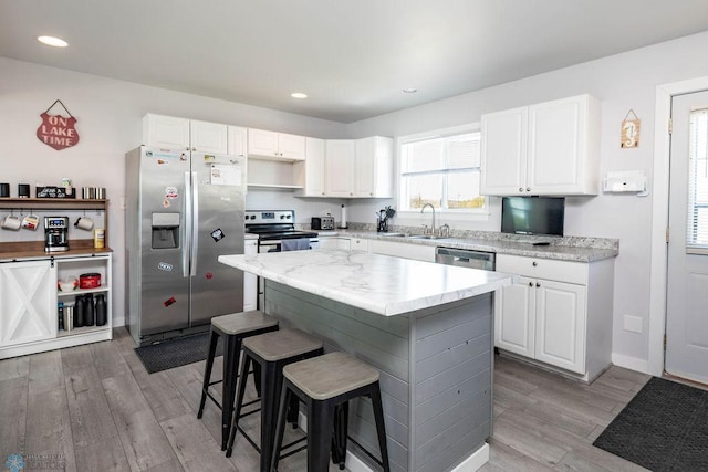 12606 Abbey Lake Ln, Lake View Twp, MN 56501 - kitchen with stainless steel appliances, a sink, light wood-type flooring, a kitchen breakfast bar, and white cabinetry