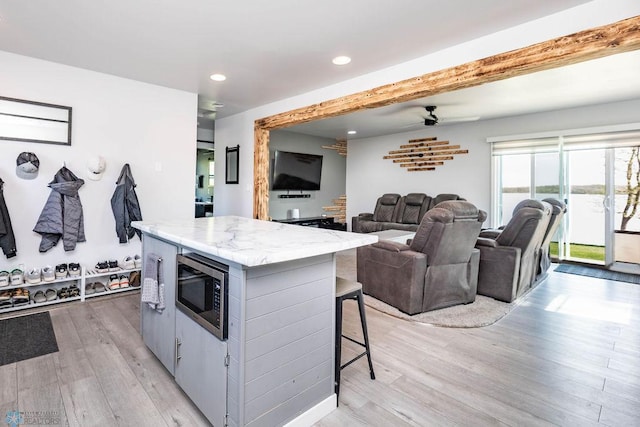 12606 Abbey Lake Ln, Lake View Twp, MN 56501 - kitchen with stainless steel microwave, light wood-style floors, a kitchen island, recessed lighting, and a kitchen bar