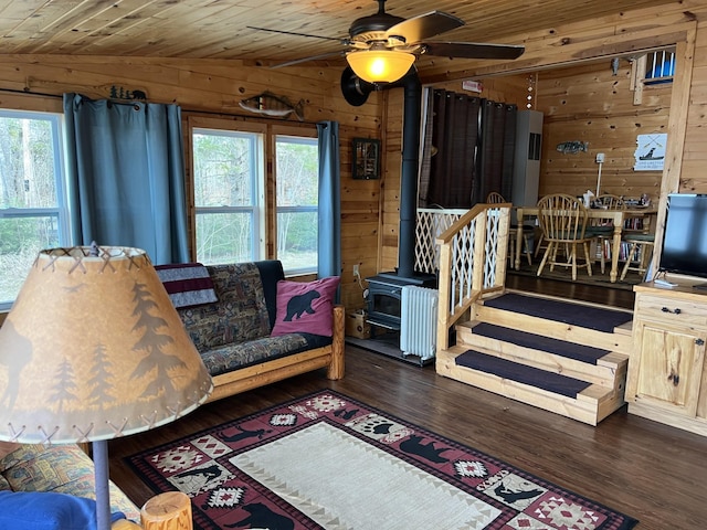 11749 Side Dr, Fine Lakes Twp, MN 55798 - living area featuring wooden walls, a wood stove, dark wood-type flooring, a ceiling fan, and wooden ceiling