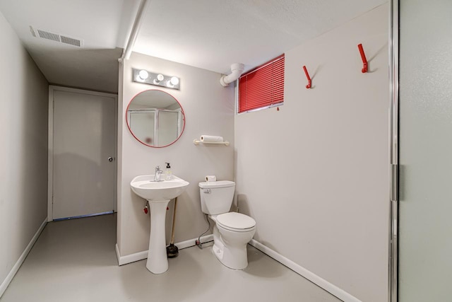 bathroom featuring concrete flooring, toilet, and baseboards