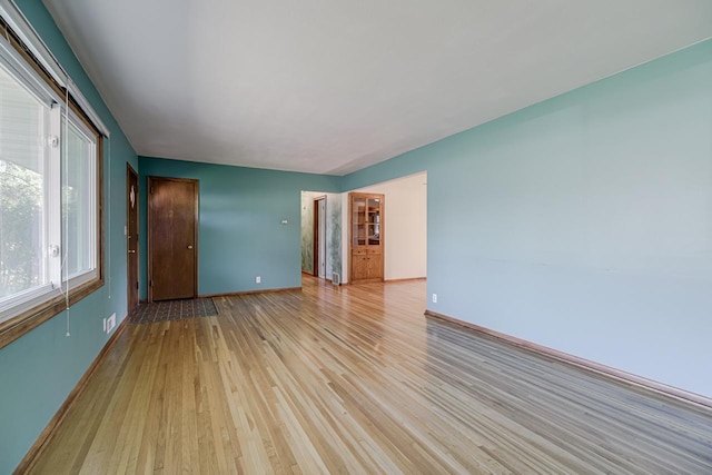 unfurnished room with light wood finished floors and baseboards