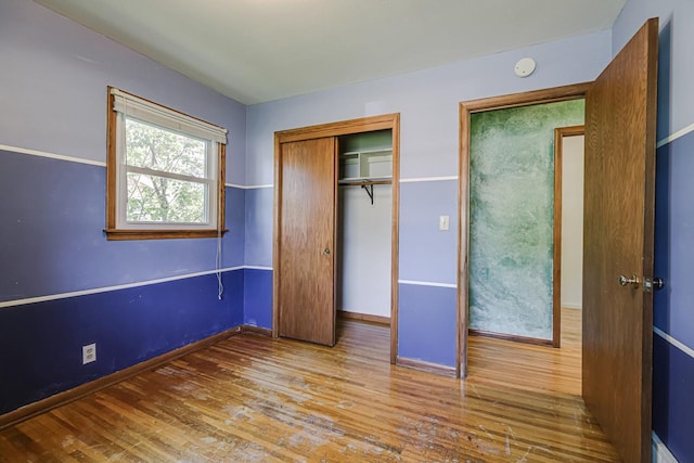 unfurnished bedroom with wood finished floors, a closet, and baseboards