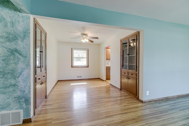 unfurnished room with light wood-type flooring, ceiling fan, and baseboards