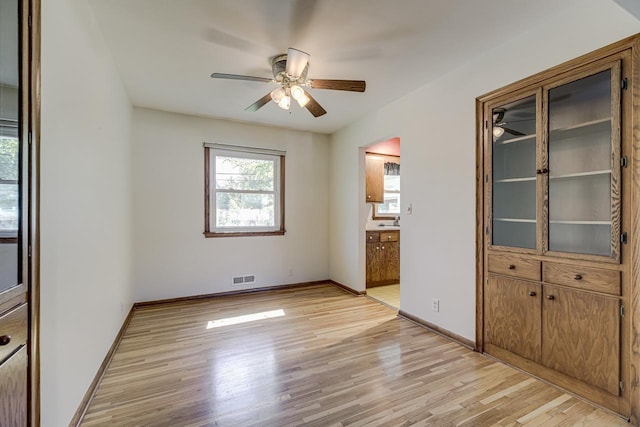 unfurnished room with a ceiling fan, light wood-type flooring, and baseboards